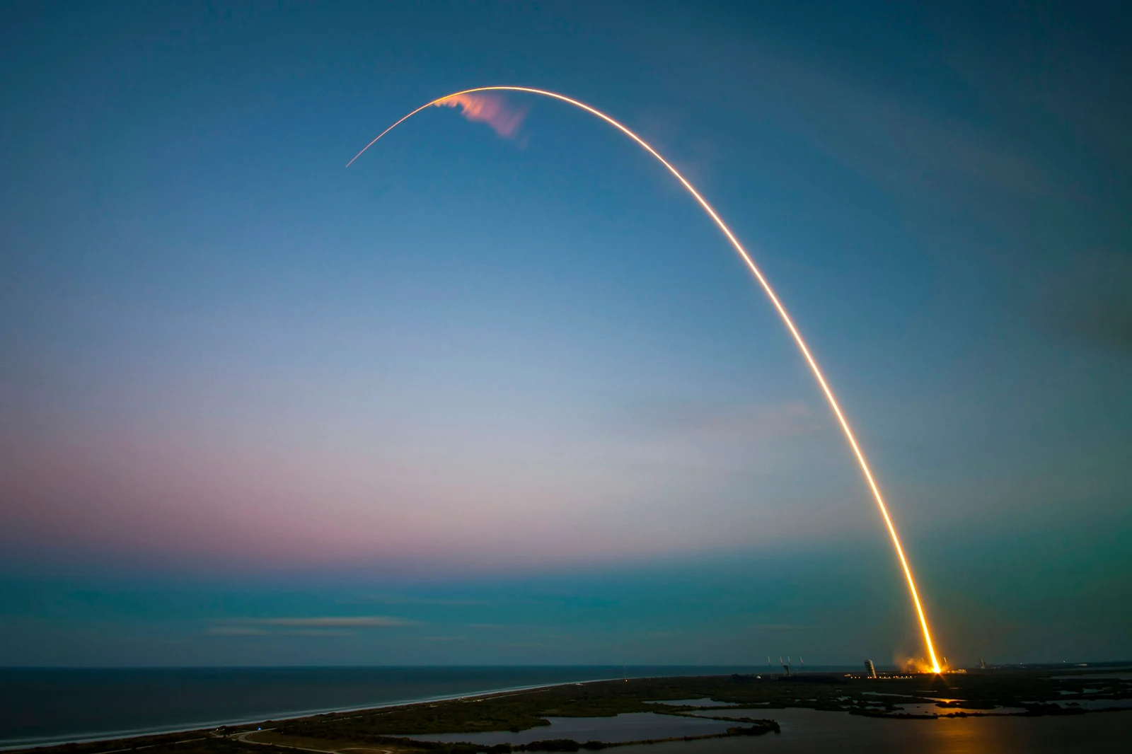The arc of a rocket launch across an evening sky